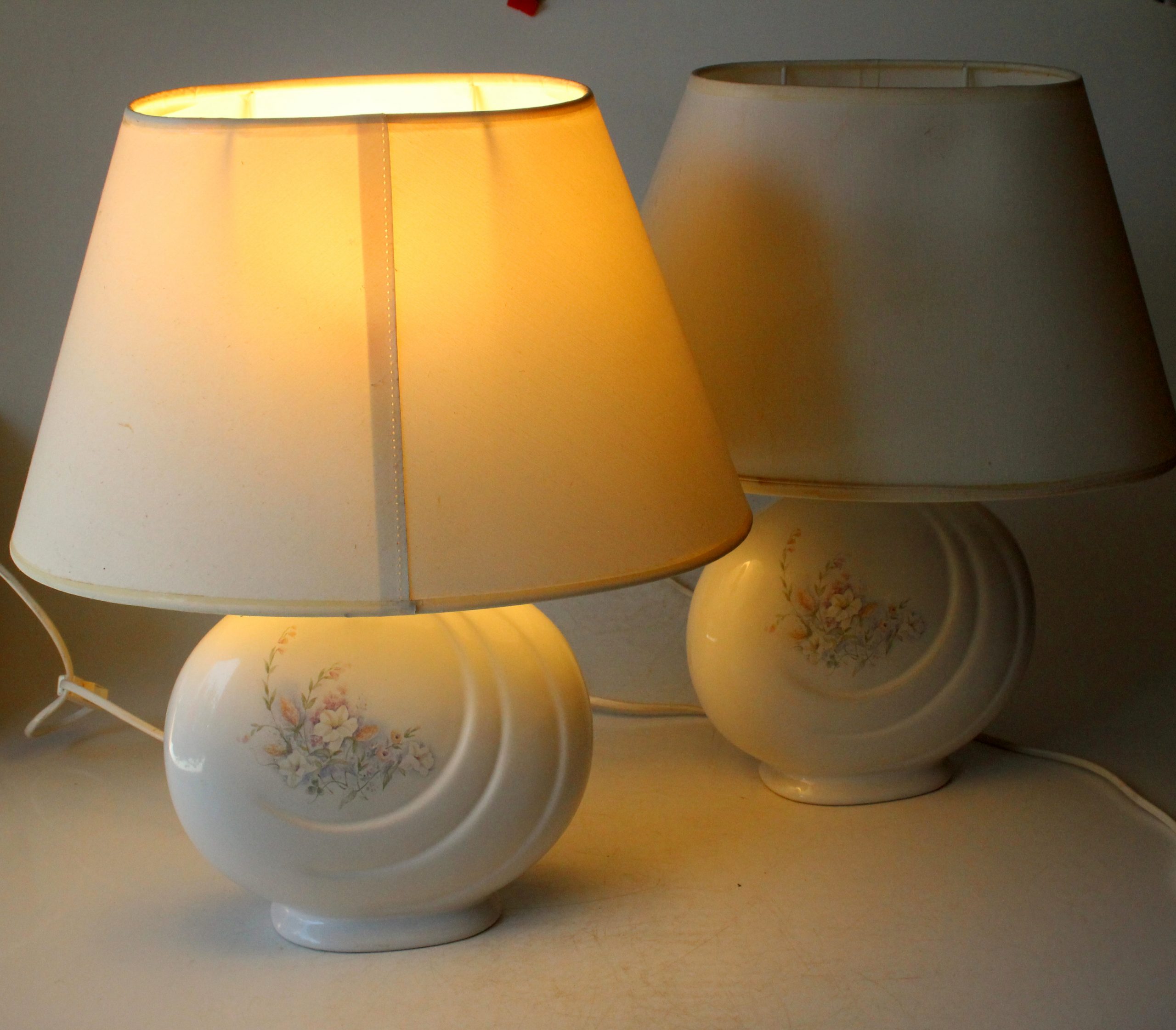 2 Bedside lamps made of white ceramic with floral motifs and with fabric lampshades, vintage from the 1970s