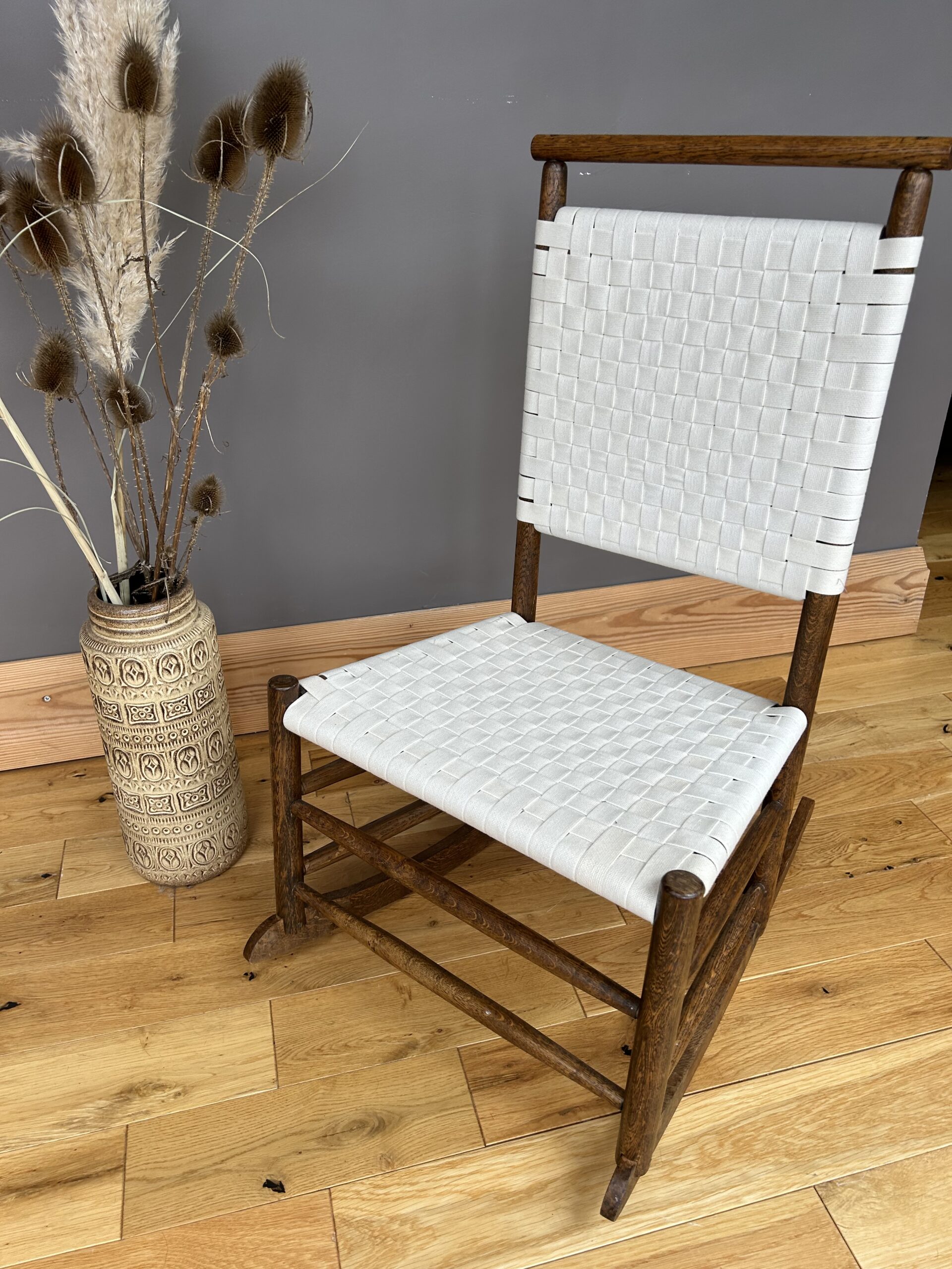 Arts and Crafts Shaker style oak rocking chair with a woven white cotton seat