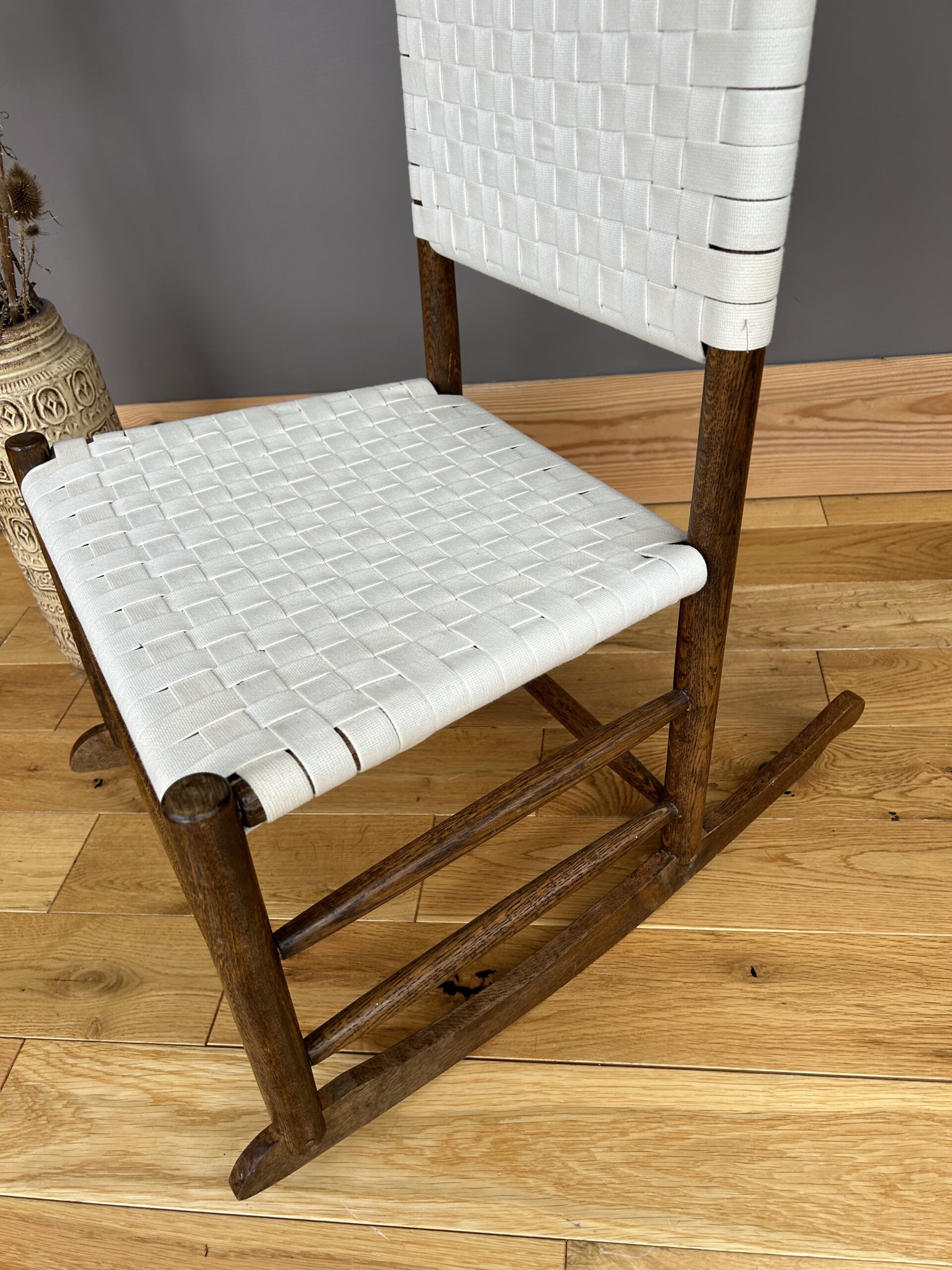 Arts and Crafts Shaker style oak rocking chair with a woven white cotton seat