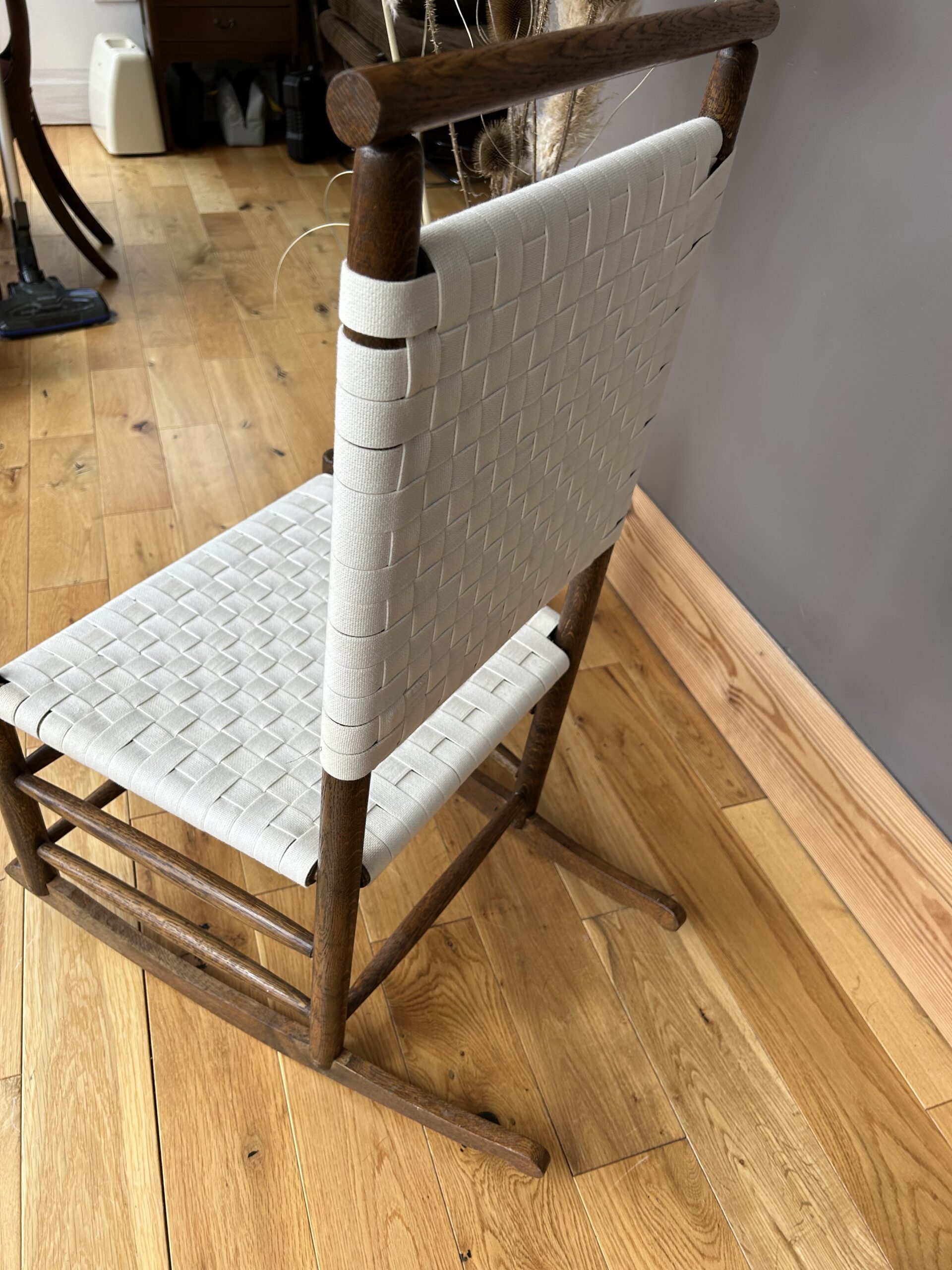 Arts and Crafts Shaker style oak rocking chair with a woven white cotton seat