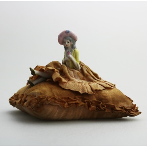 A good antique hand-painted porcelain half doll with legs on cushion C.early 20thC
