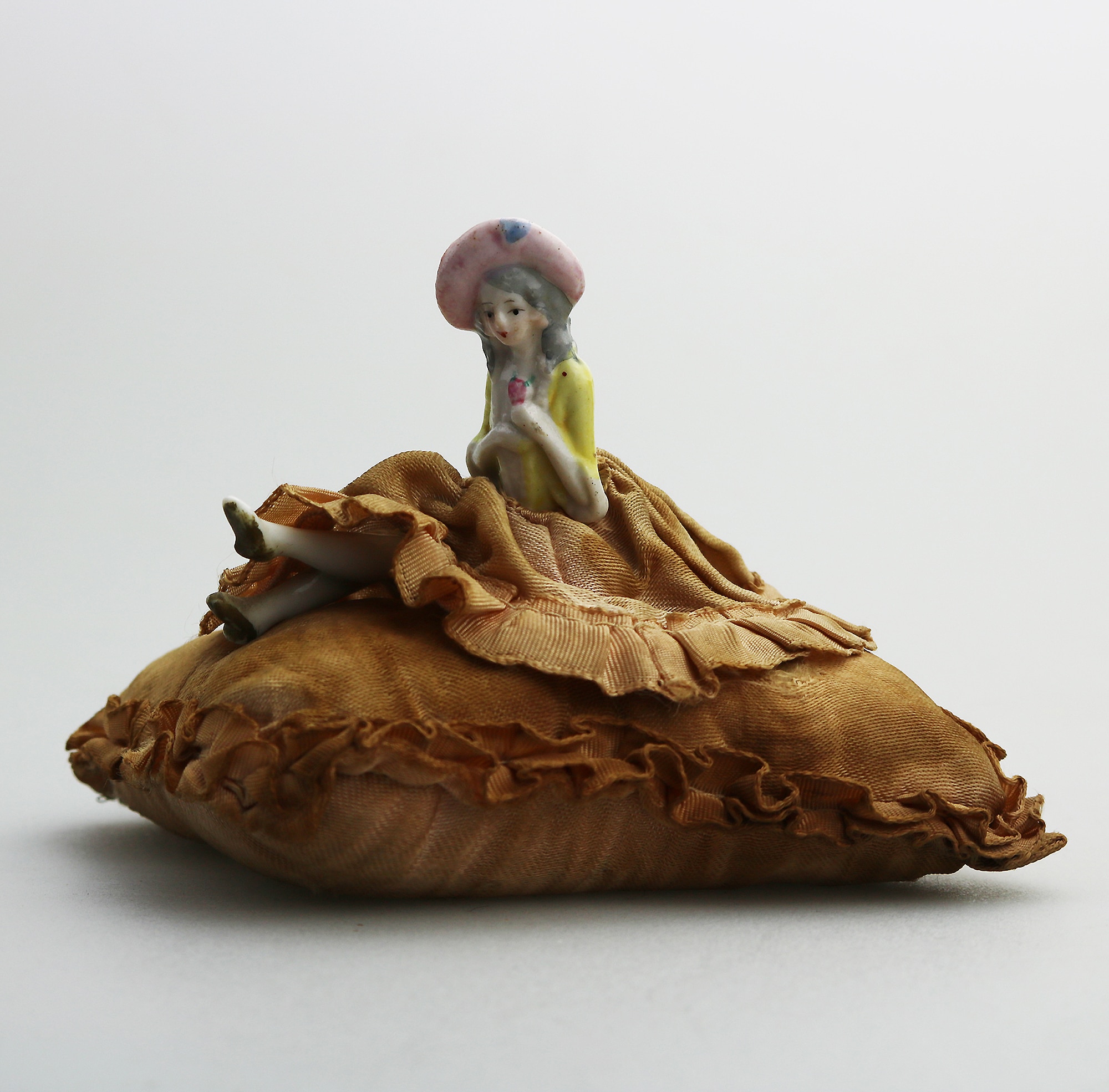 A good antique hand-painted porcelain half doll with legs on cushion C.early 20thC